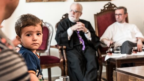 Erzbischof Heße (r.) spricht mit syrischen Christen, die in IS-Gefangenschaft waren / © Elisabeth Schomaker (KNA)