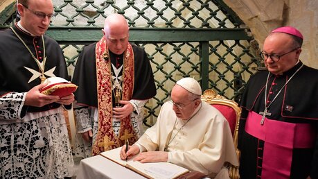 Papst Franziskus schreibt in der Paulusgrotte in Rabat (Malta) in ein Buch. Rechts Charles Jude Scicluna, Erzbischof von Malta / © Vatican Media/Romano Siciliani (KNA)