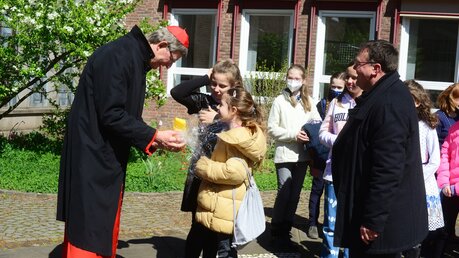 Eines der jüngsten Chormitglieder überreicht Kardinal Woelki ein Osterei aus Schokolade / © Beatrice Tomasetti (DR)
