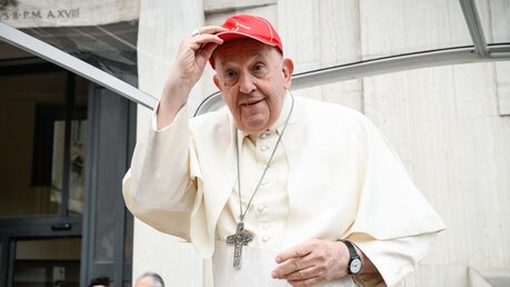 Papst Franziskus steht im Papamobil am 20. Mai 2023 im Vatikan. Er trägt eine rote Baseballkappe des Bistums Genua / © Vatican Media/Romano Siciliani (KNA)