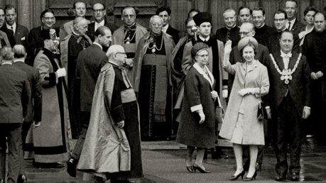 Königin Elisabeth II. wird am 25. Mai 1965 während eines Besuches des Kölner Doms von Kardinal Josef Frings und Mitgliedern des Domkapitels vor dem Portal begrüßt (KNA)