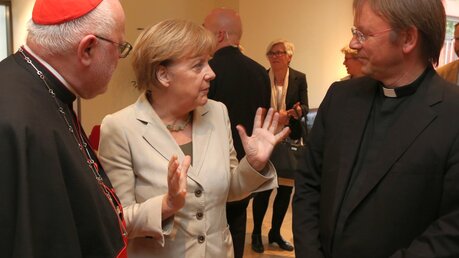 Kardinal Marx, Angela Merkel und Prälat Jüsten (KNA)