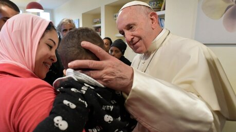 Papst Franziskus begrüßt ein Kind in der Jugendeinrichtung / © Vatican Media/Romano Siciliani (KNA)