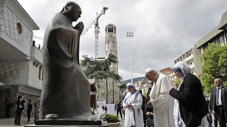Papst Franziskus (2.v.r) betet vor einer Statue von Mutter Teresa an ihrem Denkmal. / © Alessandra Tarantino (dpa)