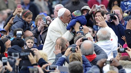Papst Franziskus küsst ein Kind nach der Generalaudienz / © Giorgio Onorati (dpa)