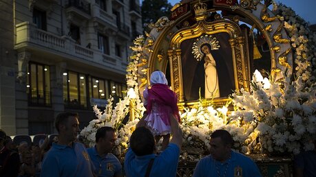 Ein kleines Mädchen wird in Madrid bei der Prozession zu Ehren der Jungfrau Paloma zum Gemälde der Jungfrau hochgehoben.  / © Francisco Seco (dpa)