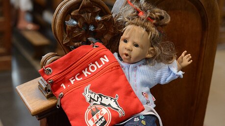 Puppe Laura ist zum ersten Mal im Kölner Dom und berichtet per Videoschalte anderen Kindern von der Kölner Eigenheit einer Fan-Andacht. / © Beatrice Tomasetti (DR)