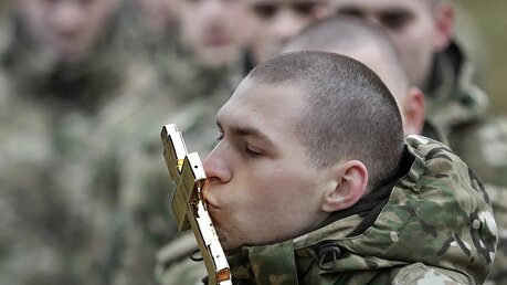 Soldaten einer Spezialeinheit des weißrussischen Innenministeriums küssen ein Kreuz / © Sergei Grits (dpa)