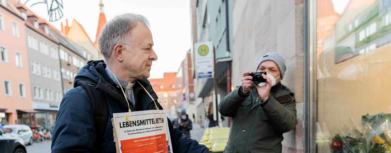 Jesuitenpater Jörg Alt verteilt vor einem Supermarkt Lebensmittel, die er zuvor bei einer Lebensmittel-Rettungsaktion aus Abfall-Containern von Supermärkten entwendet hatte / © Valeska Rehm (epd)