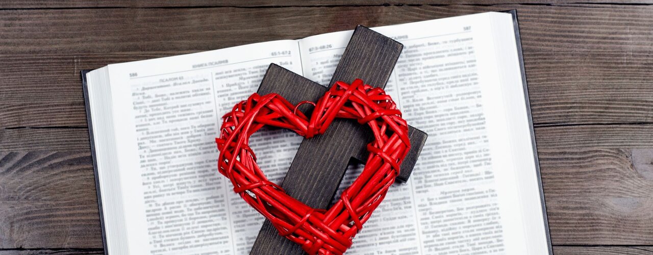 Ein Herz und ein Kreuz auf einer aufgeschlagenen Bibel / © Andrey Zhar (shutterstock)