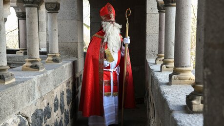 Ein Mann, als Sankt Nikolaus verkleidet, mit Bischofsstab und goldenem Buch / © Harald Oppitz (KNA)