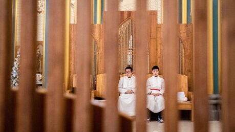 Zwei junge Männer, ein Seminarist und ein Sängerknabe, sitzen auf Stühlen während einer Messe am 13. Januar 2019 in der Kirche Xishiku in Peking. / © Gilles Sabrie (KNA)