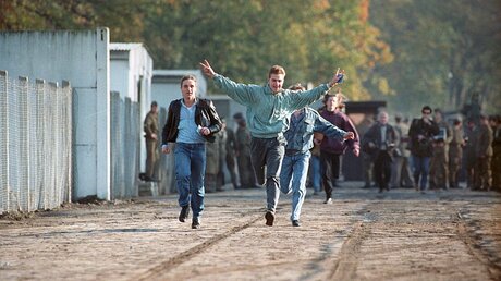 11.11.1989, Berlin: Jubelnd laufen drei junge Ost-Berliner durch einen Berliner Grenzübergang (dpa)