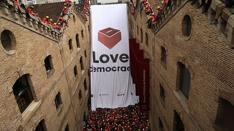 Katalanische Feuerwehrleute entfalten ein riesiges Banner mit einer Wahlurne / © Manu Fernandez (dpa)
