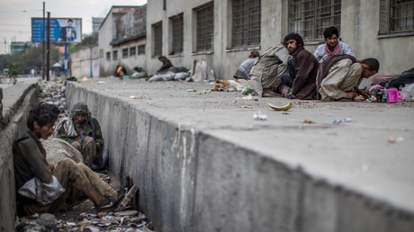 Afghanische Männer sitzen in einem verschmutzten Straßengraben / © Oliver Weiken (dpa)