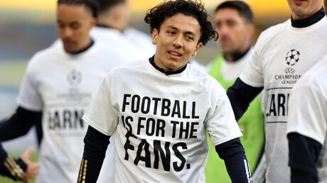 Aus Protest gegen eine geplante europäische Super League:  Ian Poveda von Leeds United trägt beim Aufwärmen ein T-Shirt mit der Aufschrift "Football Is For The Fans" / © Clive Brunskill (dpa)