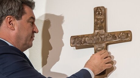 Bayerns Ministerpräsident Markus Söder hängt ein Kreuz auf / © Peter Kneffel (dpa)