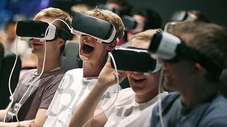 Besucher der Computerspiel-Messe Gamescom erleben mit VR-Brillen die virtuelle Realität / © Oliver Berg (dpa)