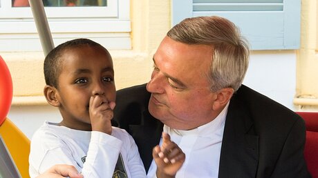 Bischof Wiesemann mit einem somalischen Flüchtlingskind  / © Elisabeth Schomaker (KNA)