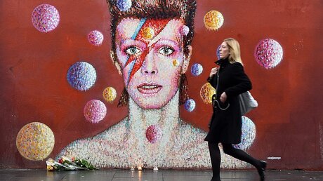 Vor einem Wandgemälde in London: Blumen für Bowie  / © Andy Rain (dpa)