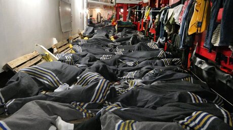 In Decken gehüllt liegen dicht an dicht Menschen an Bord des Rettungsschiffes "Ocean Viking" / © Julia Schäfermeyer (dpa)