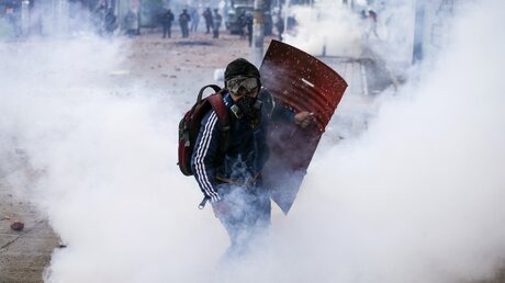 Demonstrant bei sozialen Protesten in Tränengaswolken in Bogotá, 28.05.2021 / © Ivan Valencia (dpa)