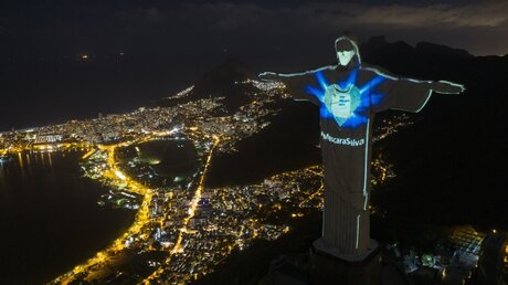 Die Christus-Erlöser-Statue in Rio ist beleuchtet, als ob sie eine Mundschutzmaske tragen würde / © Leo Correa (dpa)