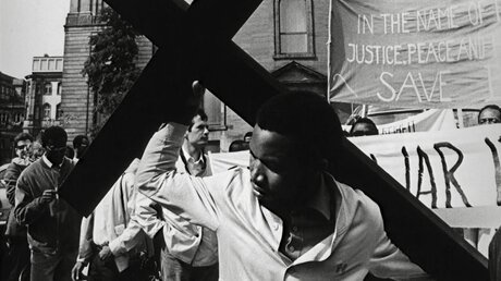 Ein in Deutschland lebender Nigerianer trägt während des Schweigemarsches gegen den "Völkermord in Nigeria" am 16. August 1968 vor der Paulskirche in Frankfurt am Main ein Kreuz.  / © N,N. (KNA)