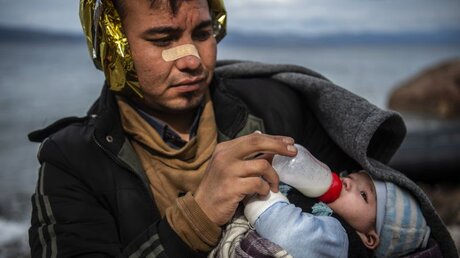 Ein Flüchtling als Afghanistan füttert sein Kind nach seiner Ankunft auf Lesbos / © Angelos Tzortzinis (dpa)