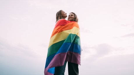 Ein homosexuelles Paar mit Regenbogenfahne / © Grusho Anna (shutterstock)