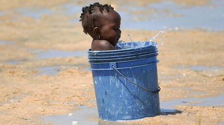 Ein kleines Kind spielt mit einem Eimer Wasser in Beira, Mosambik / © Tsvangirayi Mukwazhi (dpa)