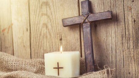 Ein Kreuz mit einer Kerze / © Billion Photos (shutterstock)