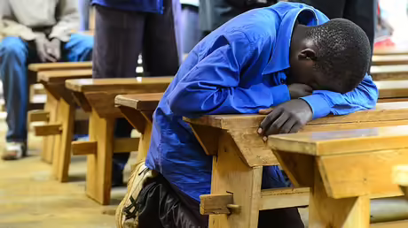 Ein Mann kniet und betet in einer Messe in Mwanda im Kongo / &copy; Harald Oppitz (KNA)