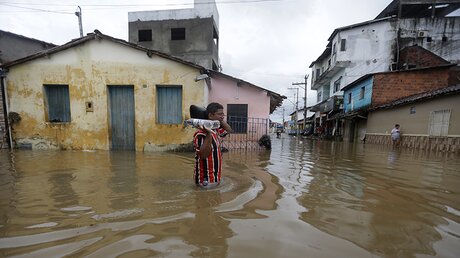 Ein Mann watet durch eine überflutete Straße im Nordosten Brasiliens. / © Lucio Tavora/XinHua (dpa)