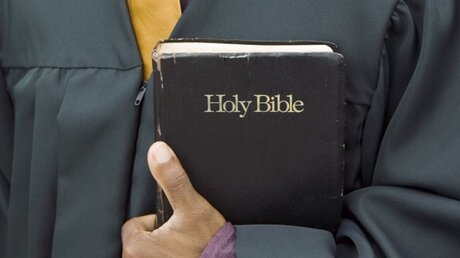 Ein Pfarrer hält die Bibel in der Hand / © sirtravelalot (shutterstock)