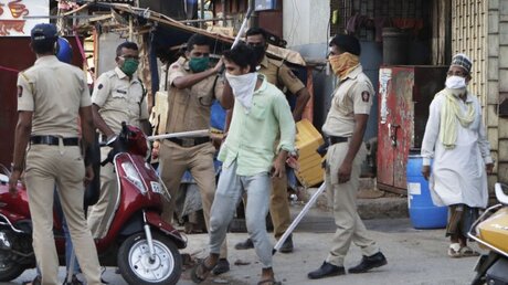 Indien: Ein Polizist holt mit seinem Schlagstock gegen einen Jugendlichen in einem Slum aus / © Rajanish Kakade/AP (dpa)