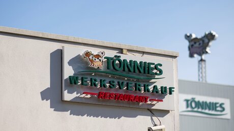 Ein Schild weist auf den Werksverkauf und das Restaurant der Firma Tönnies hin / © Guido Kirchner (dpa)