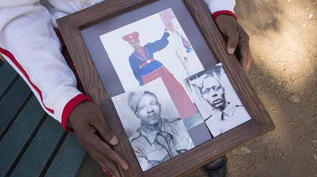 Ein Vertreter der Herero-Gemeinde zeigt Fotos seiner Vorfahren, die vor dem Völkermord in Namibia zu Beginn des 20. Jahrhunderts nach Botsuana geflohen sind. / © Gioia Forster (dpa)