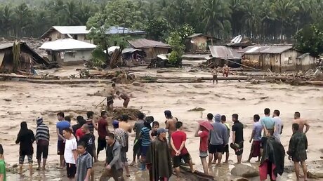 Ein Videostandbild zeigt Dorfbewohner, die versuchen, in Lanao Del Norte (Philippinen) über ein reißendes Hochwasser zu gelangen. / © Aclimah Disumala (dpa)