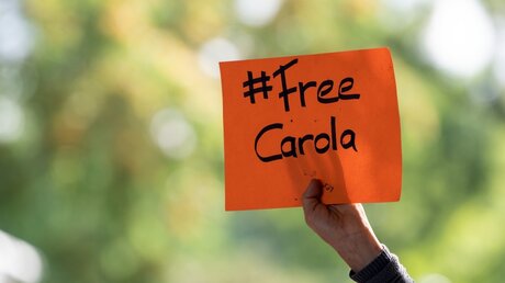 Eine Demonstrantin hält ein Schild mit der Aufschrift "#Free Carola" in der Hand / © Federico Gambarini (dpa)