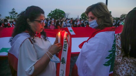 Eine Frau aus der libanesischen Gemeinschaft hält eine Kerze während einer Mahnwache zum Gedenken an die Opfer der massiven Explosion im Hafen von Beirut / © Michel Euler (dpa)