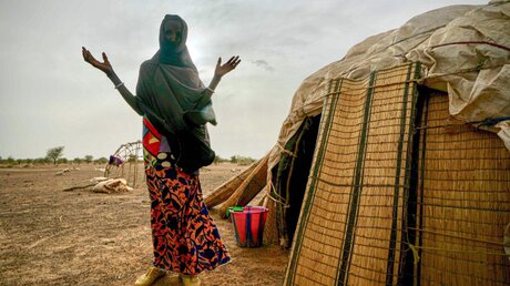 Eine Frau in Burkina Faso steht neben einer Hütte der Vereinten Nationen / © Giles Clarke (dpa)