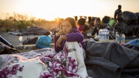 Eine Frau sitzt am Rande einer Straße in der Nähe des ausgebrannten Flüchtlingslagers Moria / © Socrates Baltagiannis (dpa)
