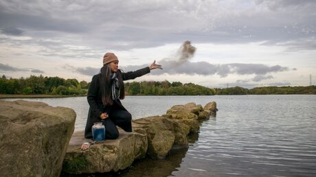 Eine Frau wirft die Asche eines Verstorbenen in den Fluss / © DnG Photography  (shutterstock)
