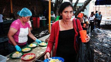 Eine freiwillige Helferin verteilt Essen an Migranten aus Venezuela / © Manuel Rueda (KNA)
