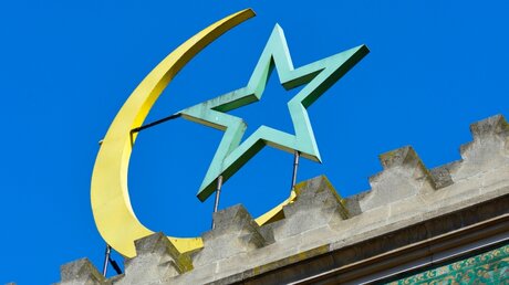 Eine gelbe Mondsichel mit blauem Stern steht auf dem Dach der Großen Moschee von Paris / © Frederic Soreau (KNA)