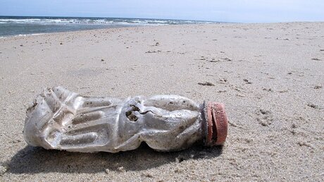 Eine Plastikflasche liegt am Strand  / © Wayne Parry (dpa)