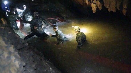 Eine Suchmannschaft, die eine Höhle betritt, in der eine Gruppe Jugendfußballer und ihre Trainer gefangen waren.  / © Tham Luang Rescue Operation  (dpa)