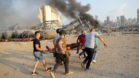Helfer bringen ein Opfer nach der Explosion im Hafen Beiruts in Sicherheit / © Hussein Malla (dpa)