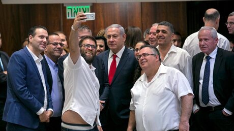 Erinnerung an die Verabschiedung des Nationalitätsgesetzes: Der israelische Abgeordnete Oren Chasan (Mitte l) macht ein Selfie mit Benjamin Netanjahu (M) / © Olivier Fitoussi (dpa)